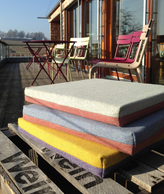 Sitz Kissen aus Schurwolle auf Weinkisten gestapelt auf Terrasse. Chair cushions from new wool on wine box on terrace